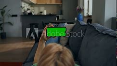 A woman holds a mobile phone with a green screen horizontally in her hands watching video, rear view, an unrecognizable person