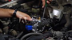 Auto mechanic installs LPG reducer vaporizer in car engine. Hands fix low pressure regulator for gas conversion. Sequential multipoint LPG injection setup. Automotive maintenance, fuel system upgrade.