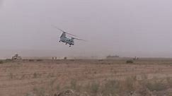 Chinook Helicopter Flies By Left ot Right in the Background of a Humvee Stopped Along a Rural Road in Afghanistan
