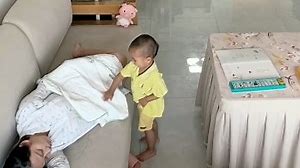 Precious toddler covers sleeping mother with a blanket