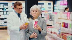 Male pharmacist gives advice to a mature woman on what product intimate hygiene to buy for personal hygiene. High quality 4k footage
