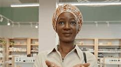 photo de verticale d'une jeune femme noire surprise recevant une carte de crédit, la regardant et faisant un paiement sans contact alors qu'elle se tenait devant la caméra dans un supermarché cosmétique