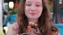 A girl happily eats seafood in a restaurant. European woman appetite. Delicious food in Albania shrimp octopus seafood. Summer restaurant on the terrace. Close-up face white skin pleasure