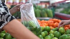 Premium stock video - Woman's hands seen selecting limes at a fresh produce grocery store - isolated