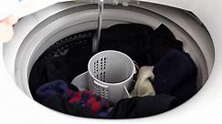 Premium stock video - Hand reaching opening cap on white washing machine appliance at home and pouring liquid into drum with full load, colorful socks and dirty wash