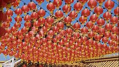 Many red traditional Chinese Lantern lamps blowing in the wind next to a temple in Kuala Lumpur, Malaysia