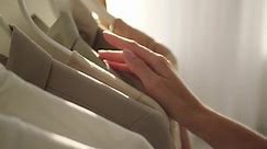 Woman running across garments on clothes rack with hand, closeup